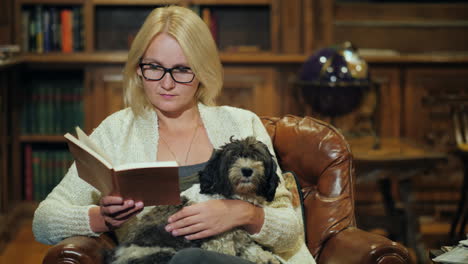 a woman relaxes in a luxurious home library holds a small dog