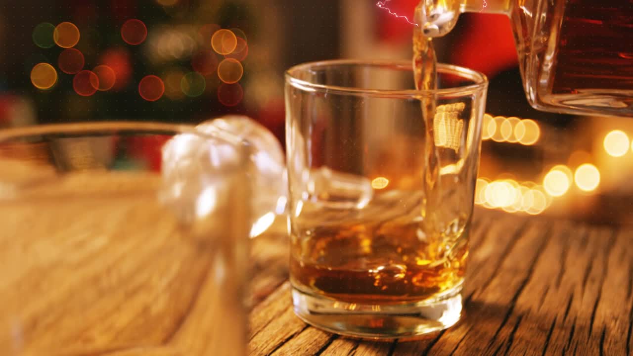 Digital overlays pulsing and fading as decanter pouring amber liquid into shot glass for holiday