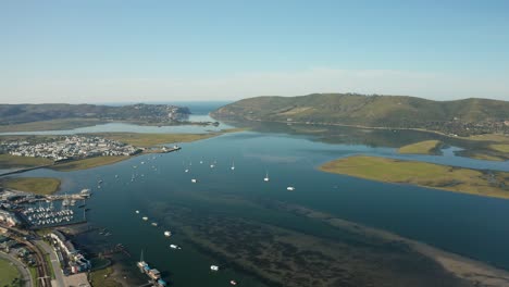 Aerial-tilt-up-of-Knysna-river-mouth-and-sailing-boats-in-the-harbor