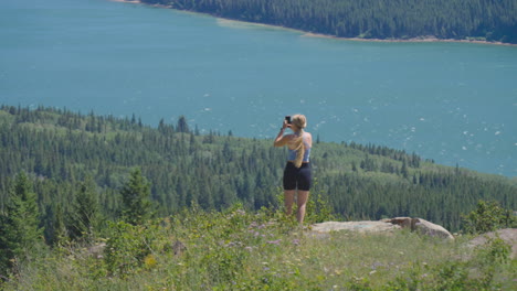 Blondes-Kaukasisches-Mädchen,-Das-Mit-Dem-Telefon-Eine-Panoramaaufnahme-Am-Rand-Einer-Klippe-Im-üppigen-Nationalpark-Mit-Gemäßigtem-Klima-Macht