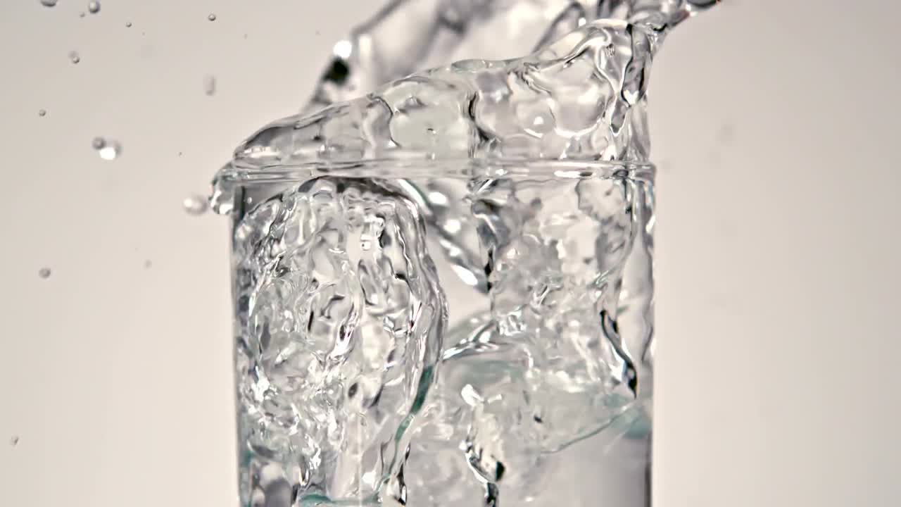 Premium stock video - Ice cubes falling into glass of water