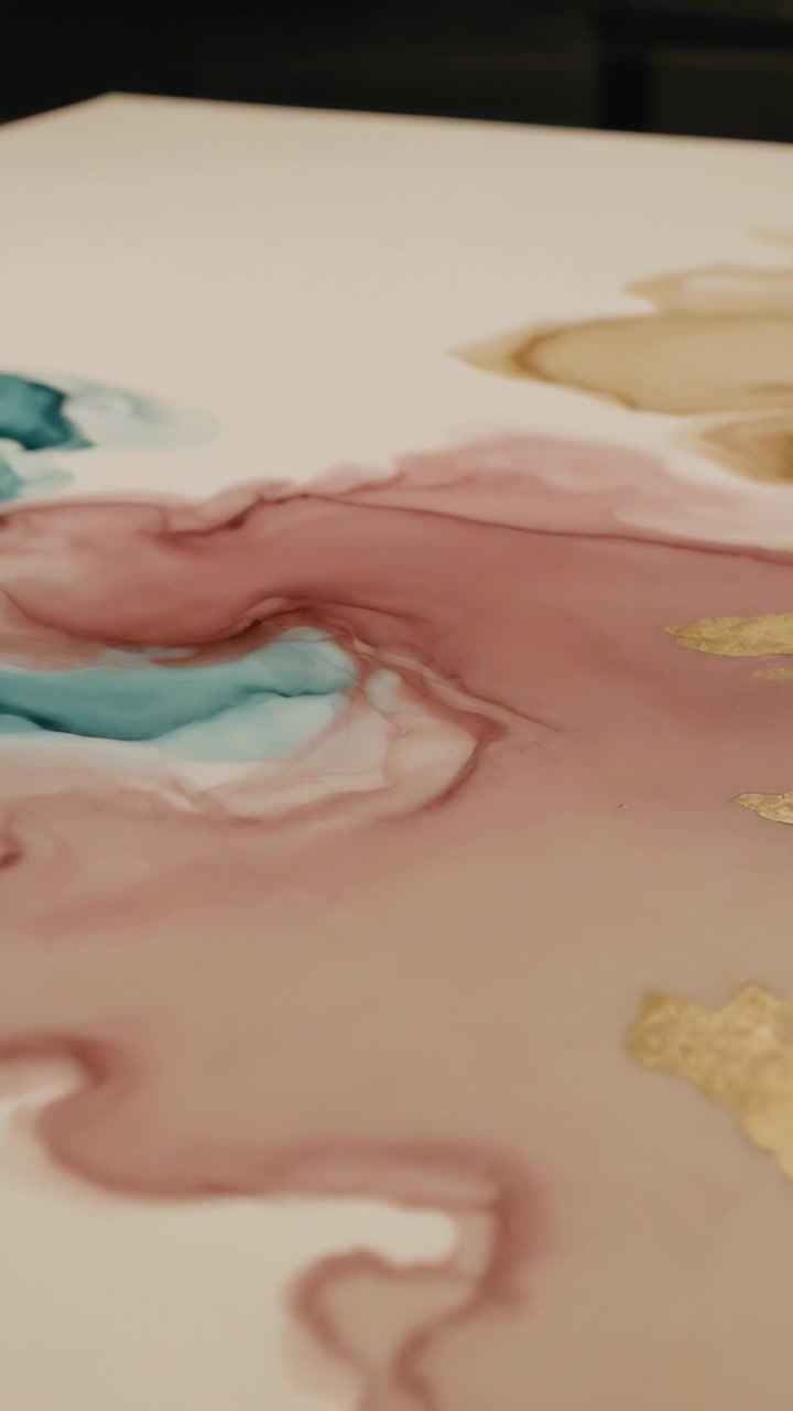 Video verticale: La telecamera si sposta su inchiostri ad alcool che si depositano su un pannello bianco per formare strati con l'oro