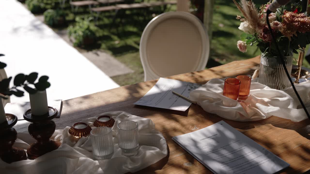 Sunlit wedding signing table with documents, candles, and floral decor
