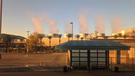 pov disparado conduciendo más allá de las chimeneas humeantes de una planta de energía, durante la puesta de sol