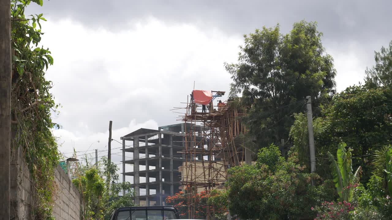 los trabajadores están construyendo un nuevo edificio utilizando maderas locales para construir andamios