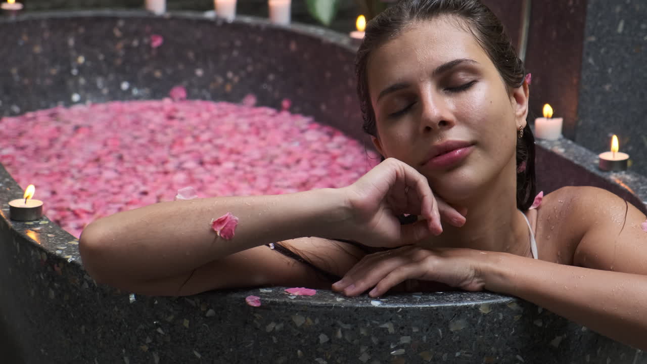 Woman enjoying a spa bath with rose petals and candles