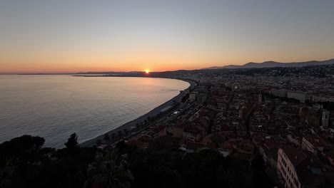Twilight sunset over the Bay of Angels and cityscape of Nice, France, with darkening skies and glowing coastline seen from Colline du Château