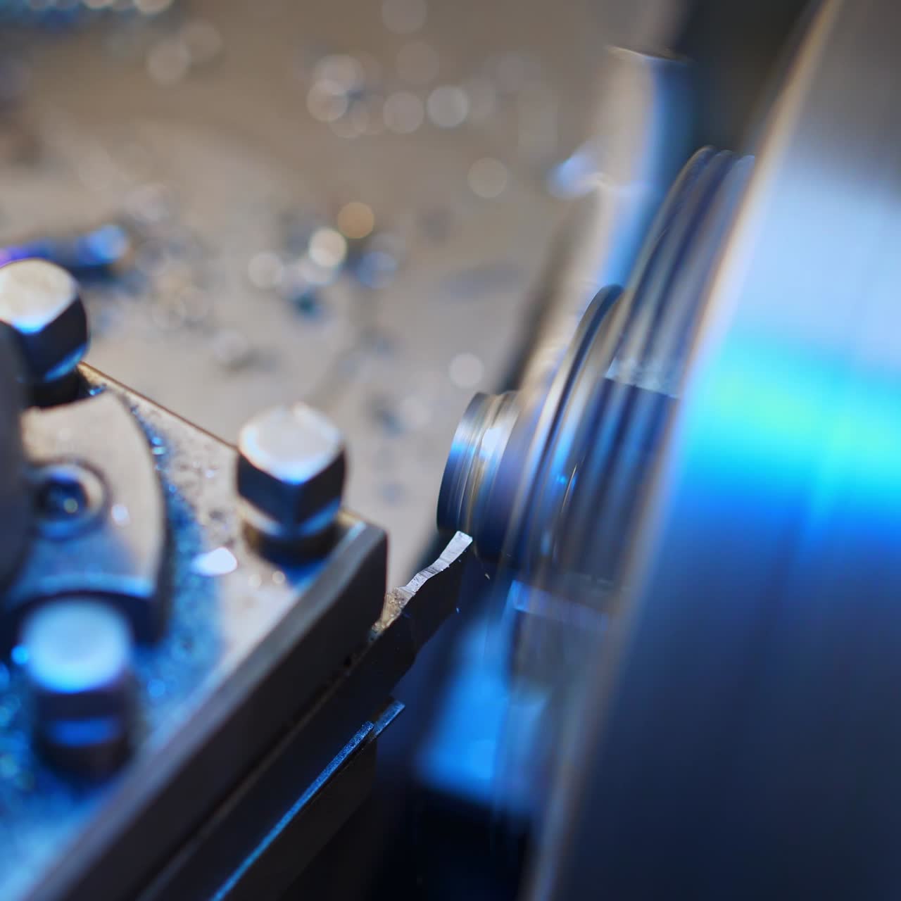 Grinding out the metal detail fastened in turner lathe. Wide metal shaft rotating to shape the piece of instrument. Close up