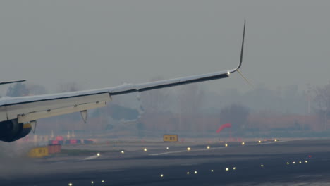 avión aterrizando en una pista de aterrizaje con niebla