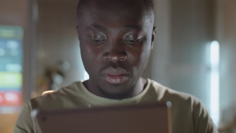 man working on digital tablet in office at night