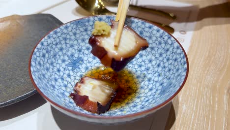 chopsticks picking up squid from a bowl