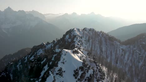 camera following the ridge line of srednji vrh looking towards kranjska gora and triglav national park. aerial view of the karavanke alps in the winter on a clear skies day