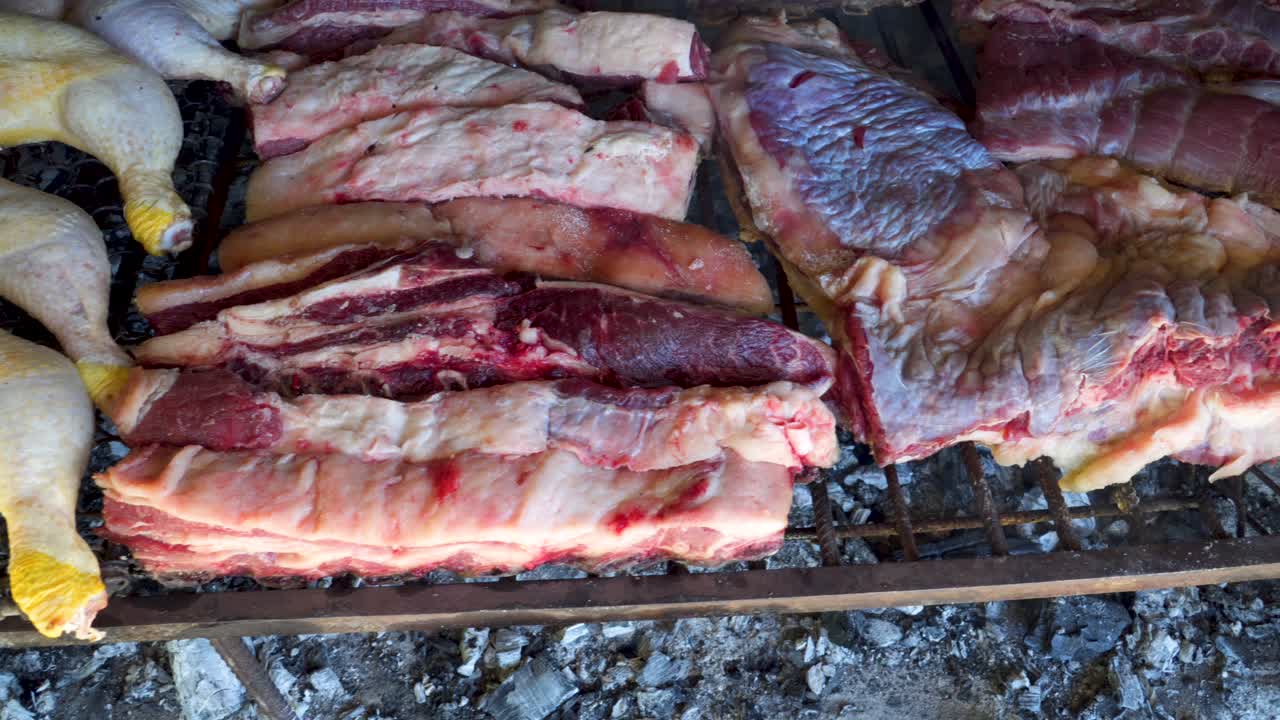 pollo argentino crudo y asado de ternera a la parrilla sobre brasas humeantes