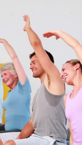 grupo de fitness sentado en pelotas de ejercicio estirando los brazos