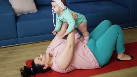 plump mother holds a chubby smiling baby in her arms at home on the floor