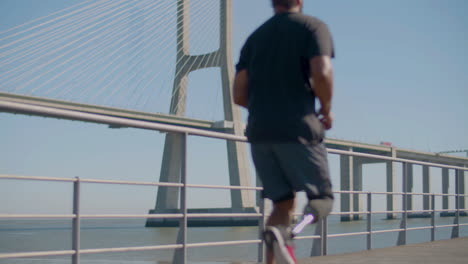 male athlete with artifical leg jogging at seashore on bridge.