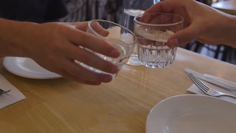 two people clinking glasses at a table