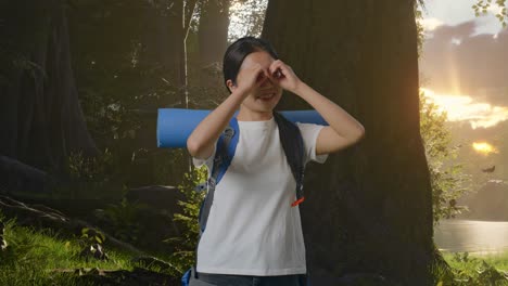 excursionista femenina asiática con mochila de montañismo sonriendo y haciendo gestos de binoculares luego mirando a su alrededor mientras explora la naturaleza del bosque