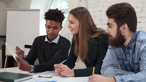 young african guy explaining something to his colleagues. happy diverse group of students or young business team working on a