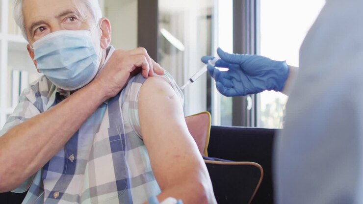 Video of hands of biracial female doctor vaccinating caucasian senior man