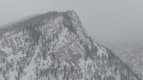 aerial shot of snow covered copper mountain peak with wild trees and misty background at colorado, usa..