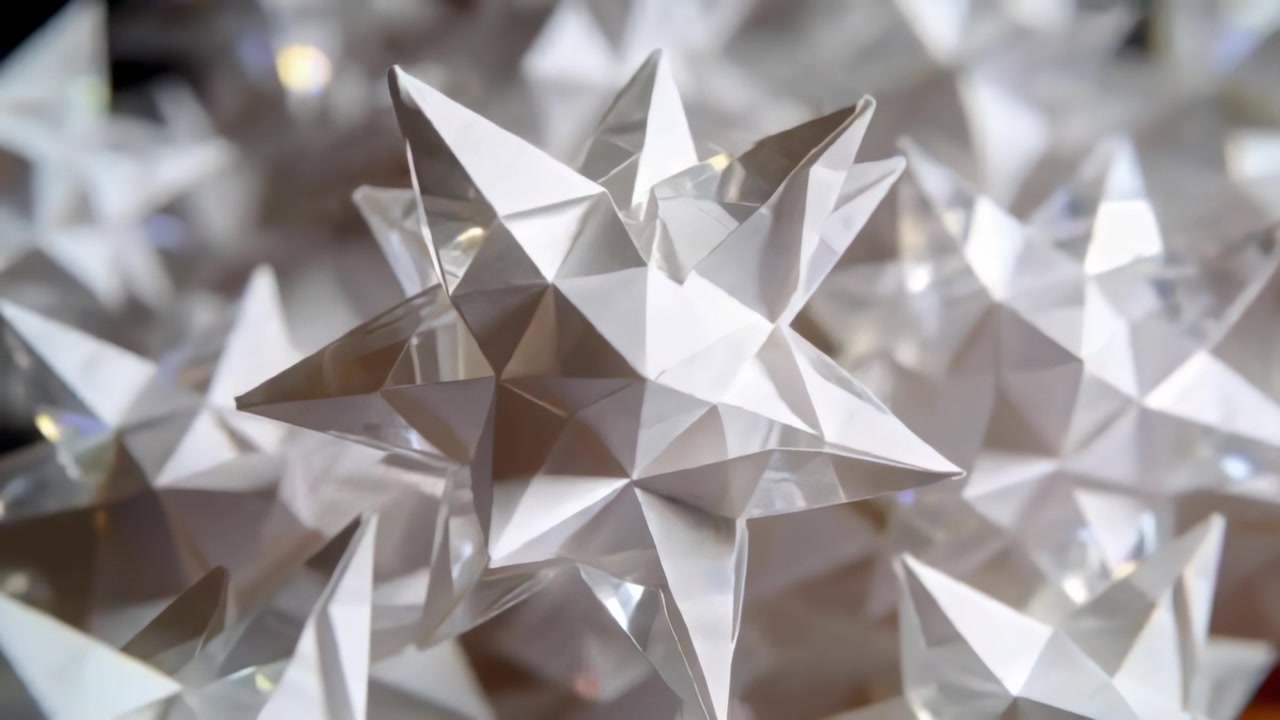 Lens pulling focus, white stellated paper star moving toward center on tabletop, showing creases