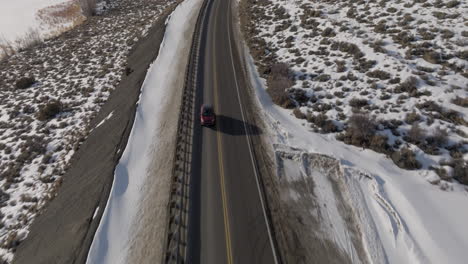 Aerial-Tilting-shot-of-a-car-driving-through-the-rocky-mountains