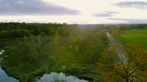 aerial footage at the pond in autumn, trees without leaves, bald stems of trees, colorful landscape around, beautiful sunset, warmia and masuria, poland