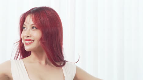 beautiful young asian ballerina woman with long red hair dancing smiling happy in the white room