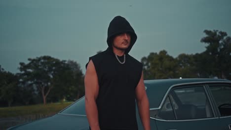 man in hoodie by classic car