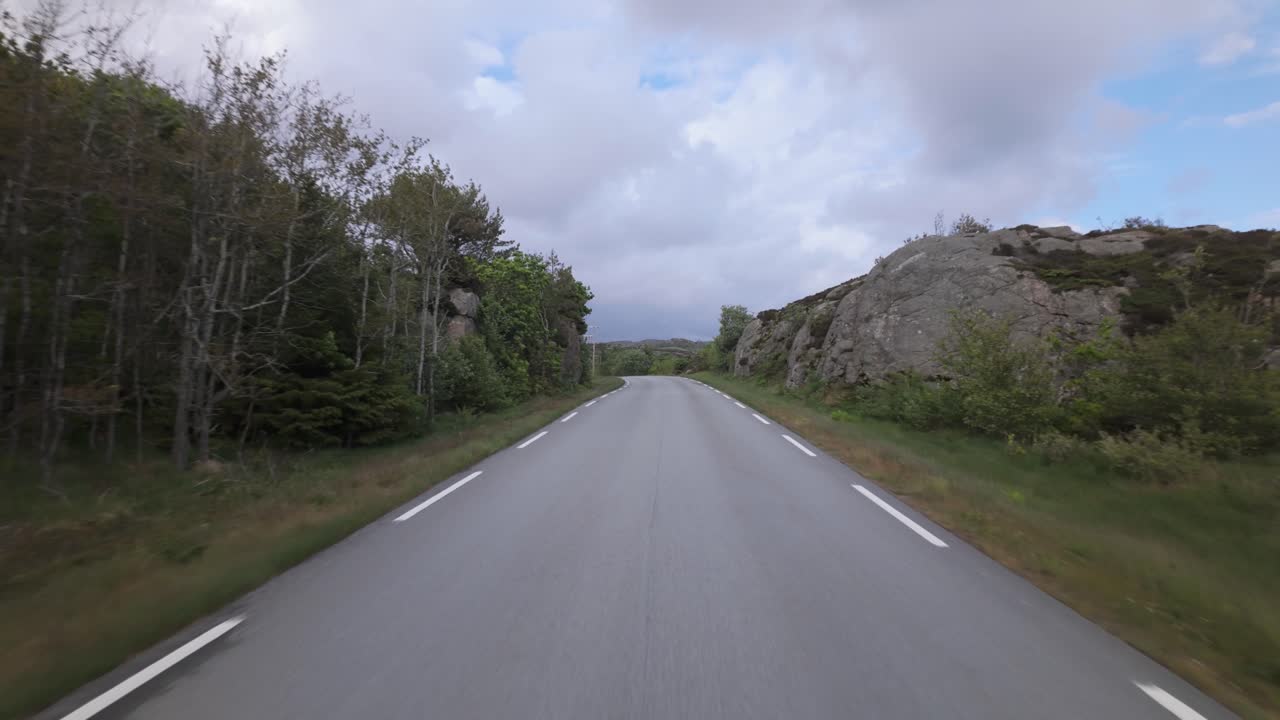 Driving On An Empty Road Through Dense Trees On A Cloudy Day. POV Shot