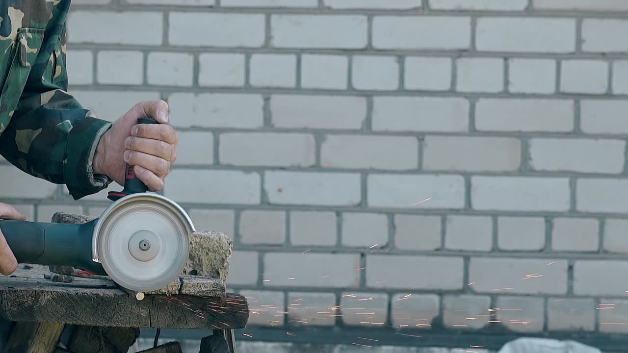 作業中のビルダーが ⁇ ハンドディスクソーを使用して金属棒を切断します ⁇