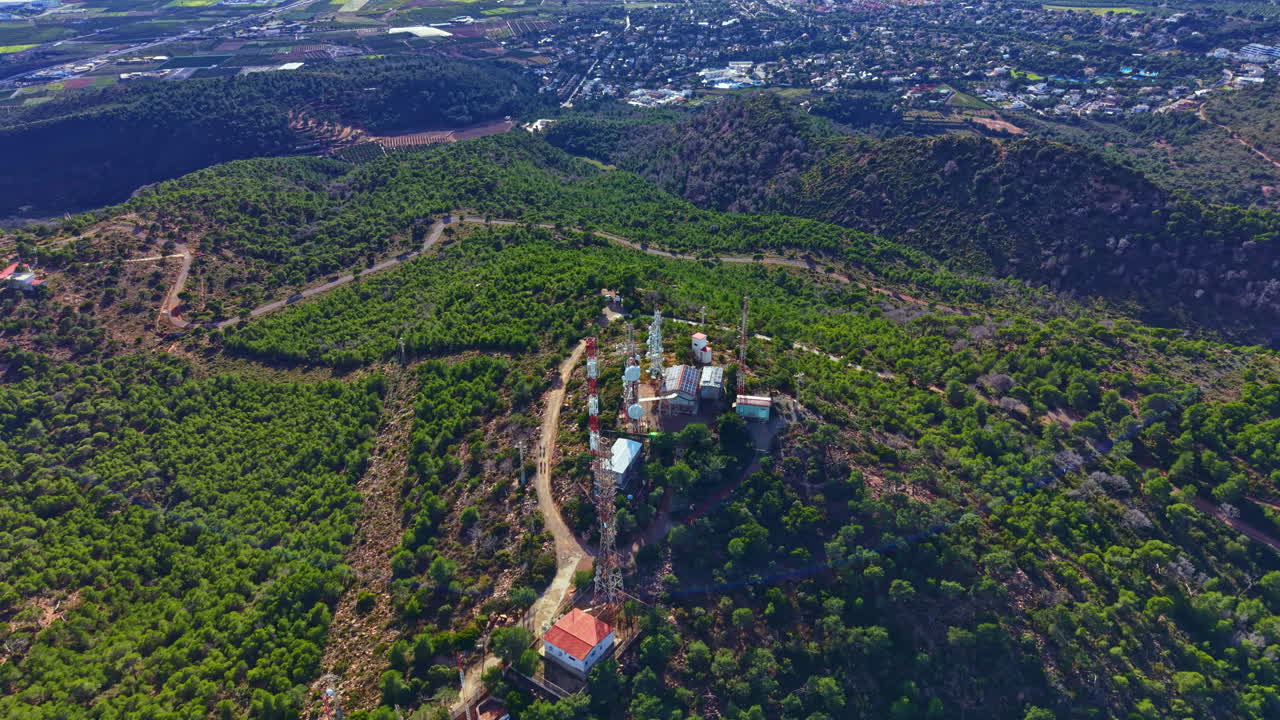 Vista panoramica di un'area boschiva con edifici su una collina, scattata di giorno dall'alto in una località rurale circondata da un centro abitato.