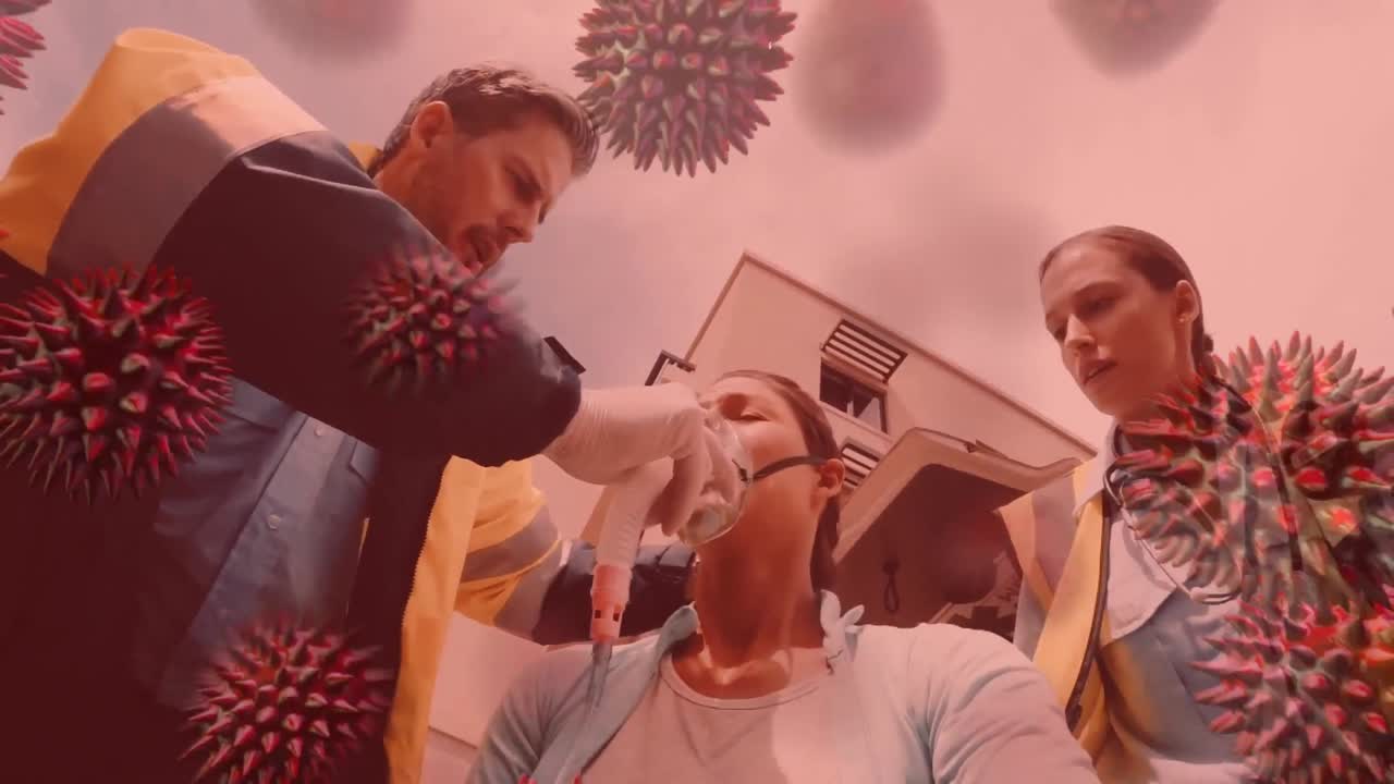 코로나19 세포가 배경에 있는 여성에게 산소 마스크를 착용하는 구급대원들에게 퍼지고 있습니다.