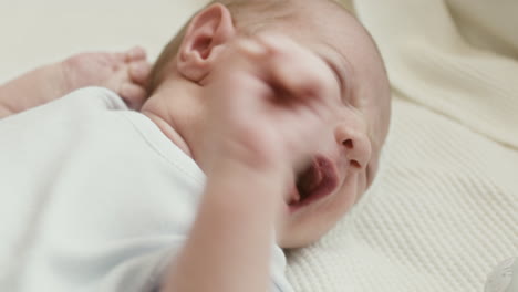 close up of a cute newborn baby lying on bed and crying 2