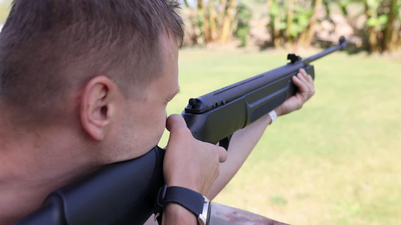 Young man shoots rifle in street shooting range 4k movie