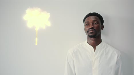 young black man leaning on the wall and looking at levitating flower