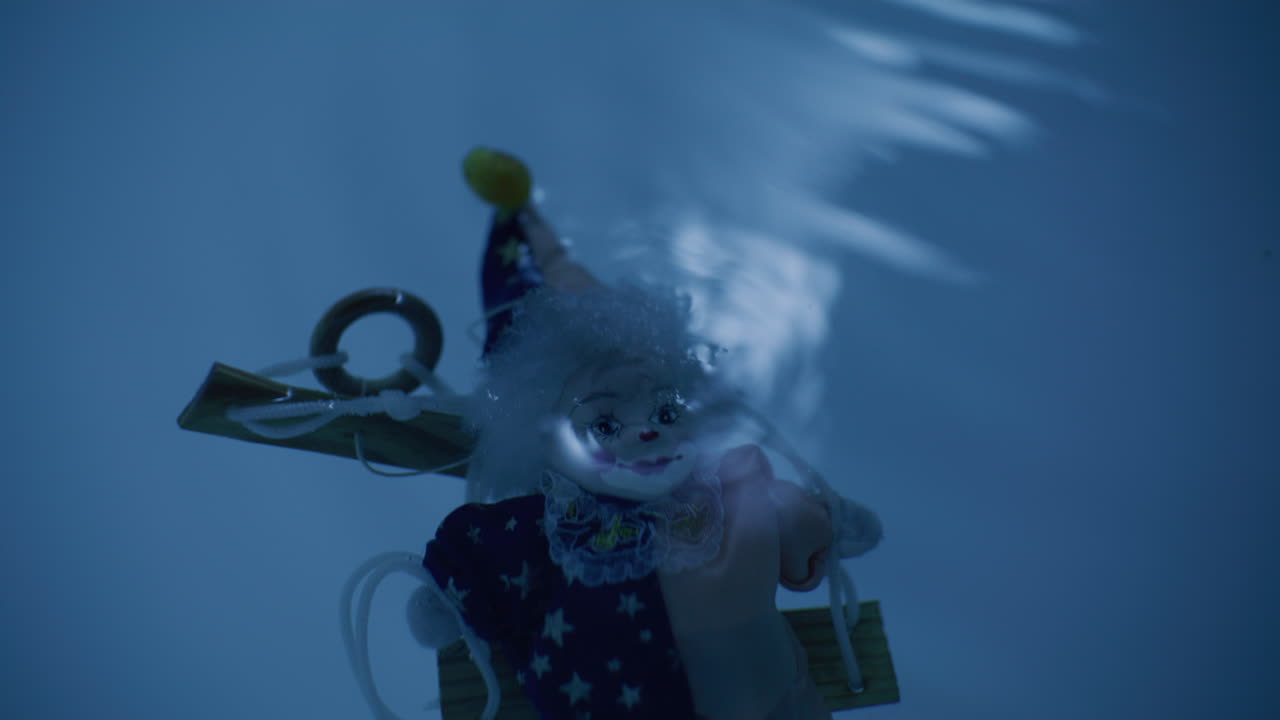 Clown submerged in water, ominous underwater scene
