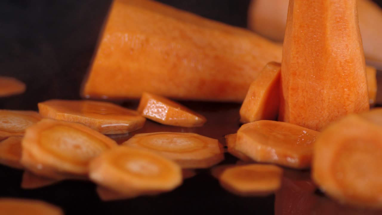 Fette di carota fresca cadono nell'acqua