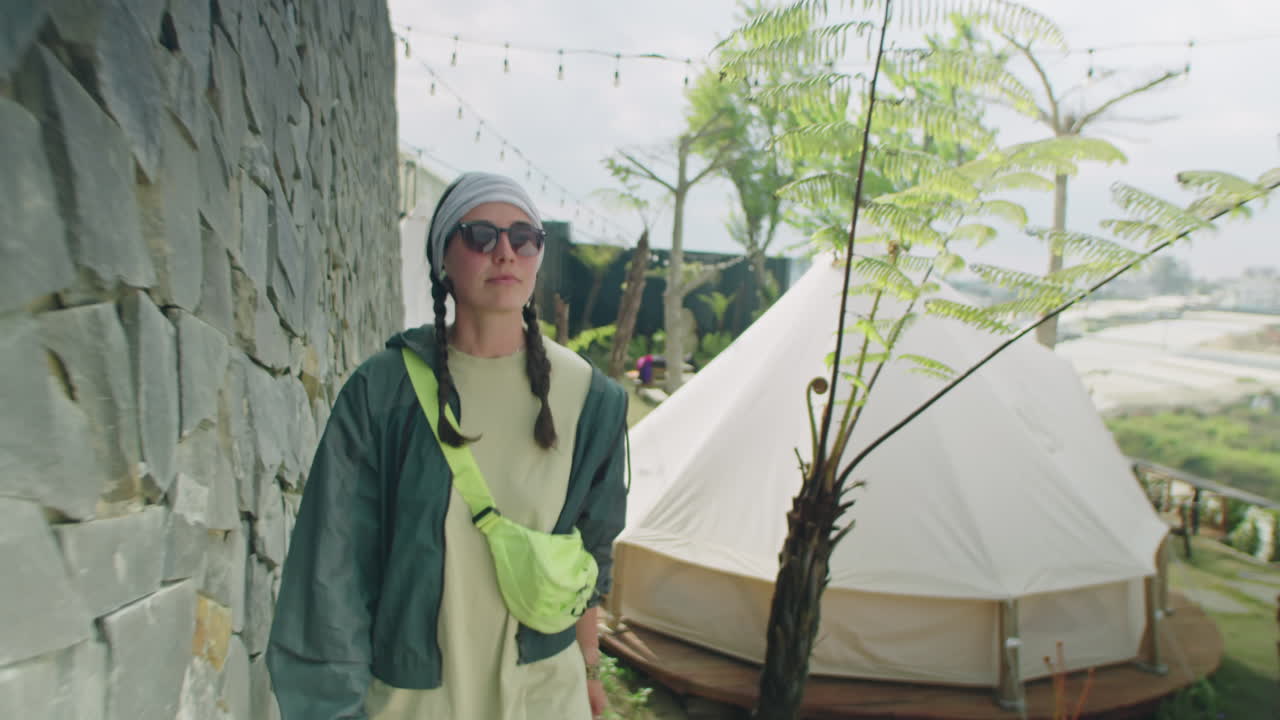 Female Tourist Walking Along Stone Wall at Glampsite