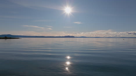 flying low over lake taupo with bright sunlight reflecting on the calm water, new zealand.