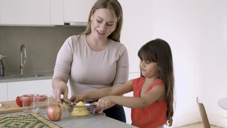 Fröhliche-Mutter-Und-Kleine-Tochter,-Die-Zitrone-Auspressen