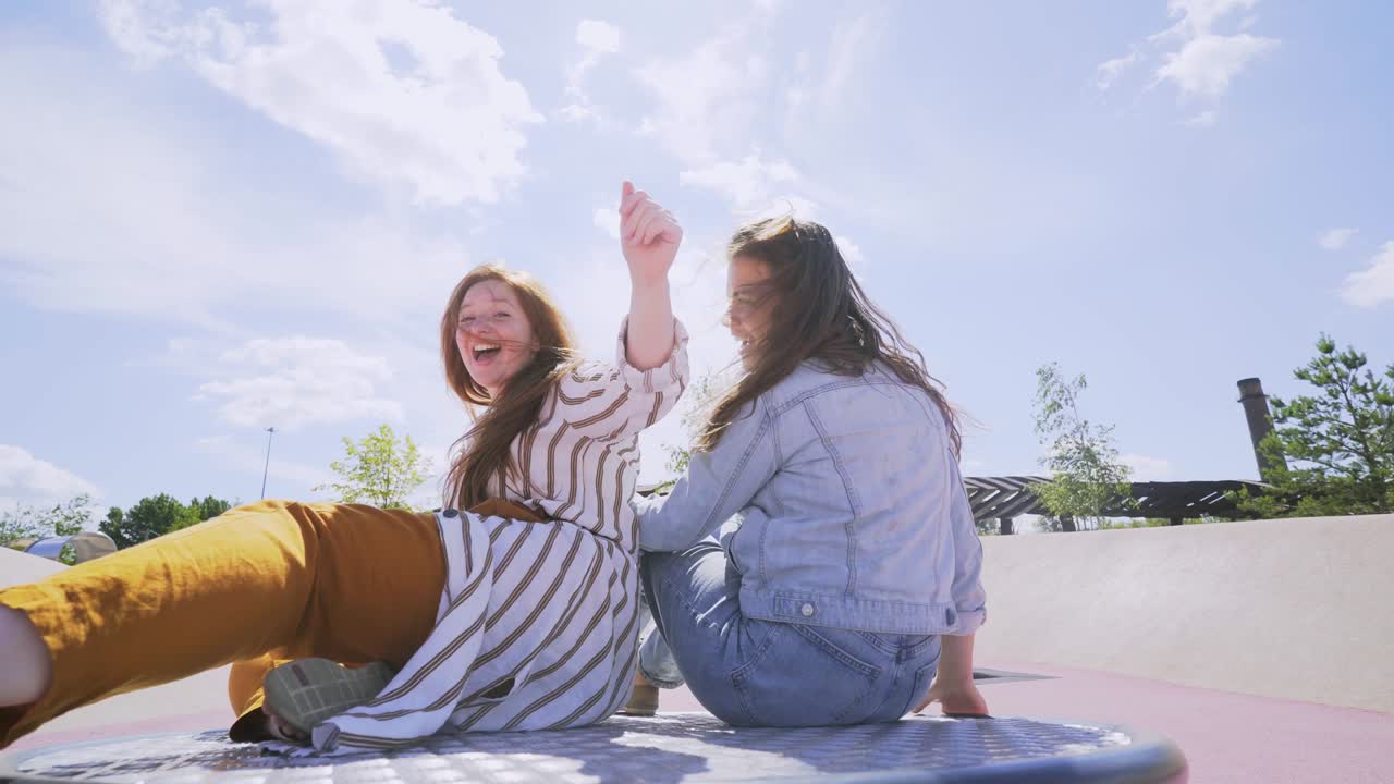 women in stylish spring clothes ride carrousel in city park