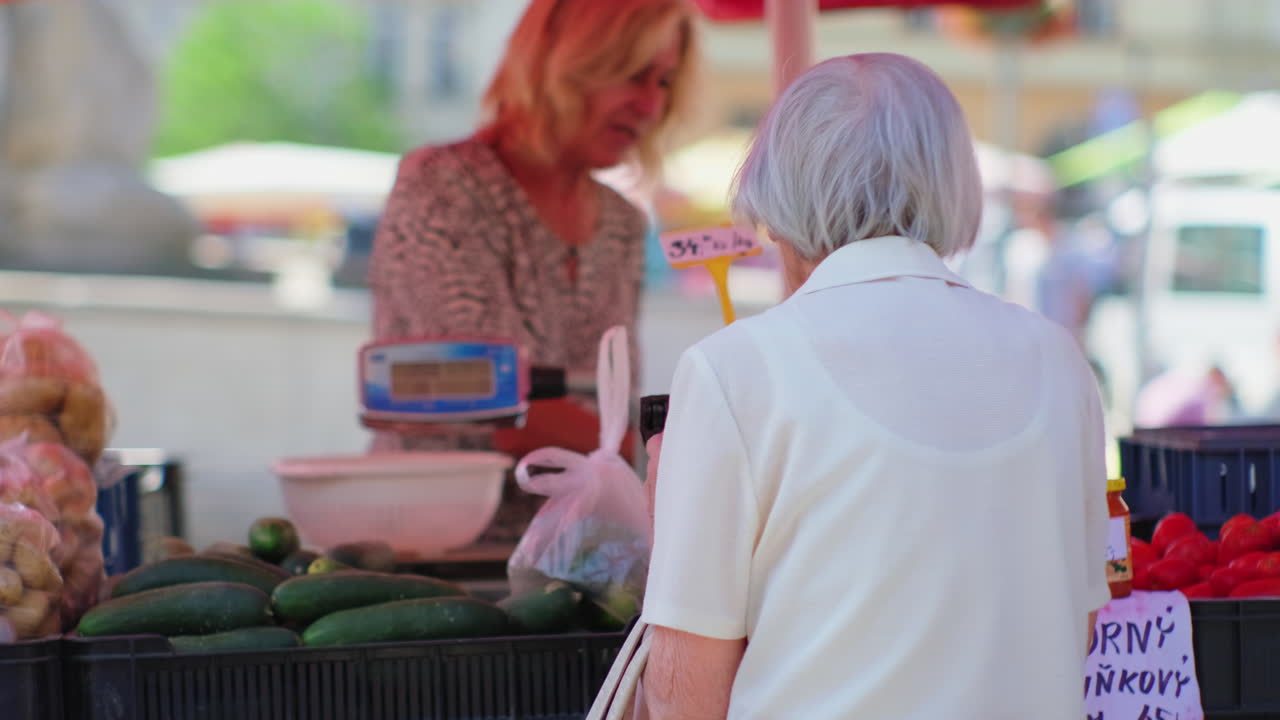 mujer anciana comprando verduras en un mercado
