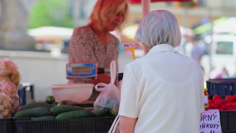 elderly woman buying vegetables at a market