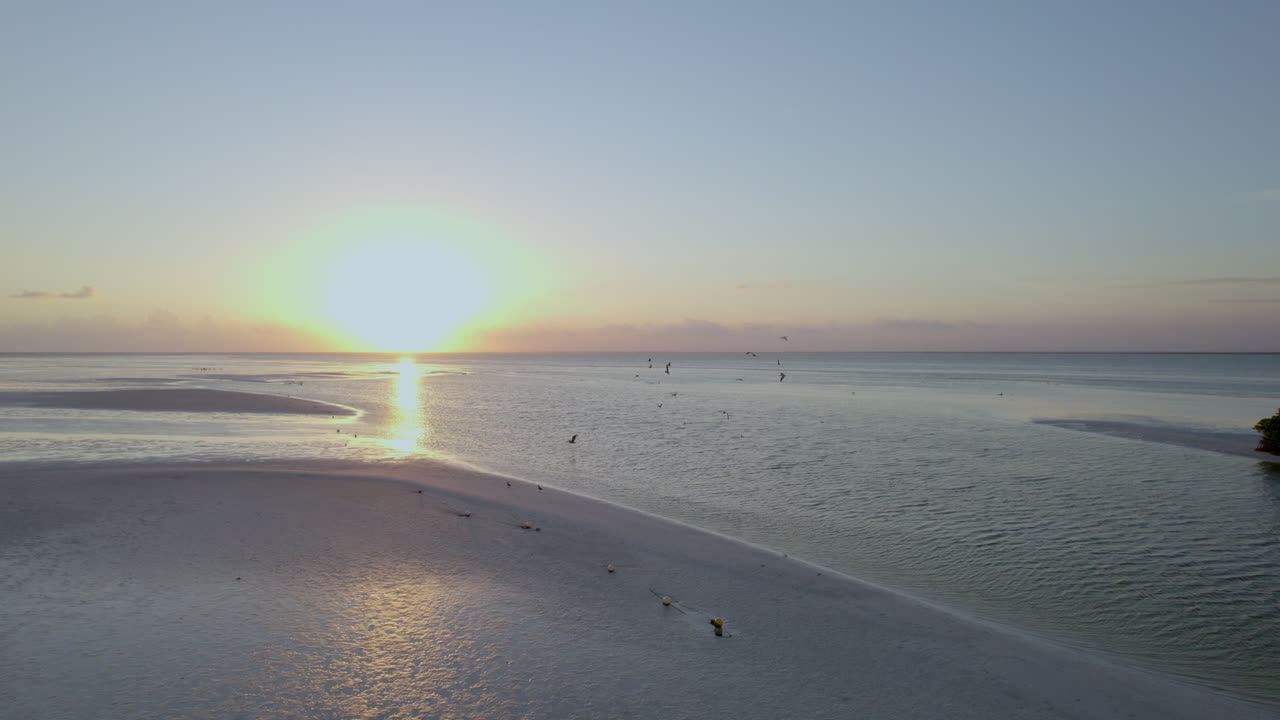 Droneoptagelse af havet med solnedgangshimmel.