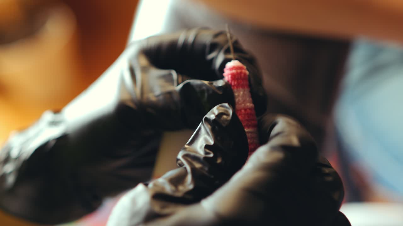 Behandschuhte Hände eines Tätowierers bereiten Nadel im Studio vor