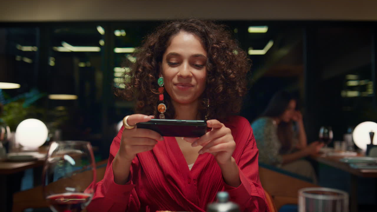 mujer de lujo tomando fotos usando un teléfono inteligente en un restaurante de lujo interior de loft.