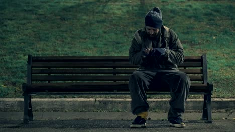 hungry lonely beggar sit on bench counting his money