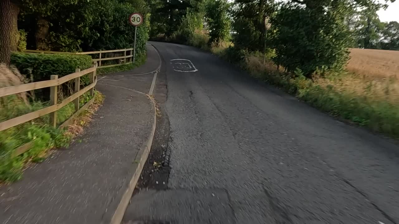 A drive along a narrow rural lane with clear road markings and lush greenery.